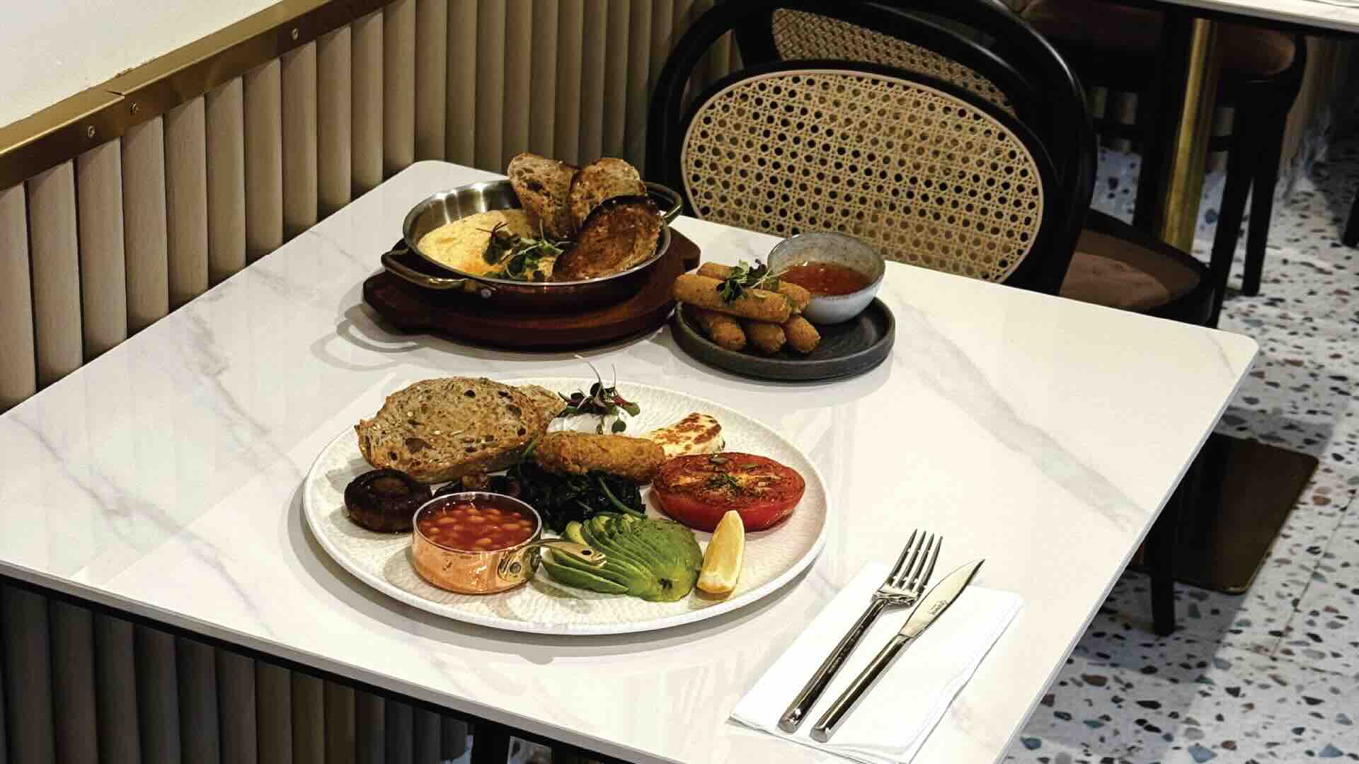 A full breakfast, fresh bread and grilled halloumi on a marble table at Lush Coffee