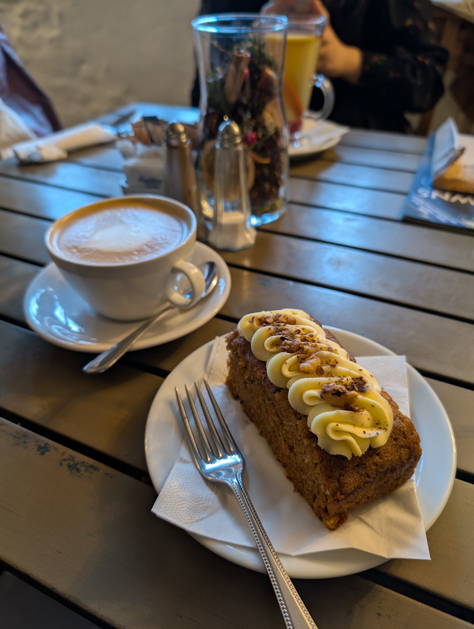 A slice of carrot cake served with a cappuccino