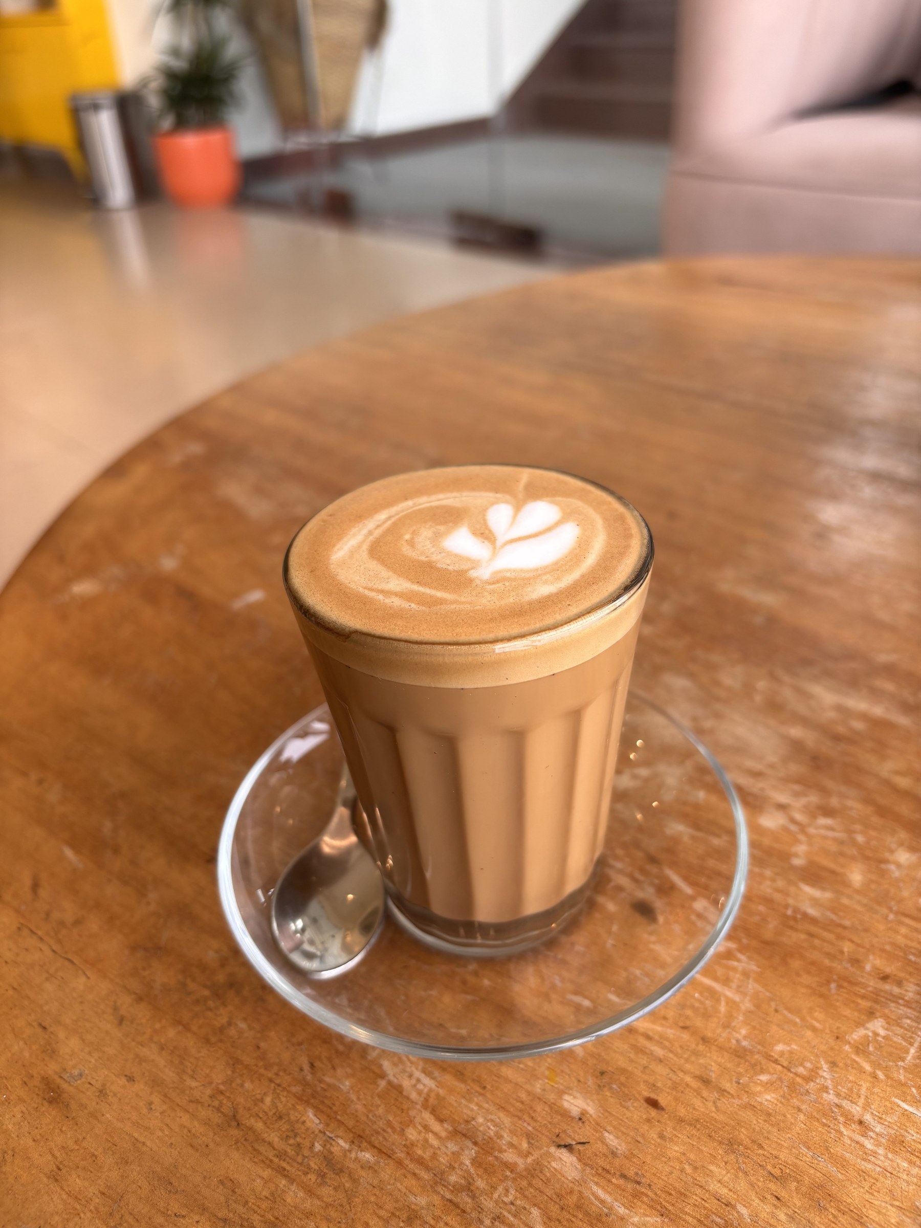 A cortado with heart latte art on a wooden table